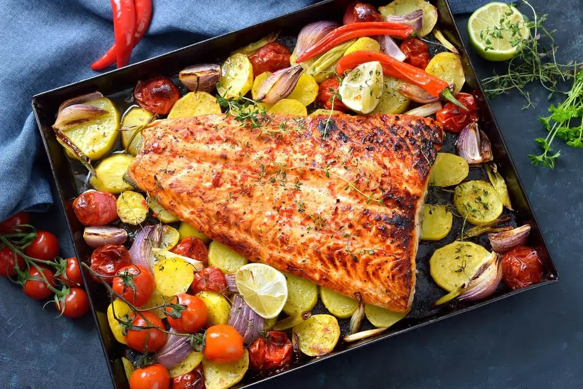Delicioso pescado al horno con patatas, tomates, cebolla y pimientos. Un plato completo y sabroso.