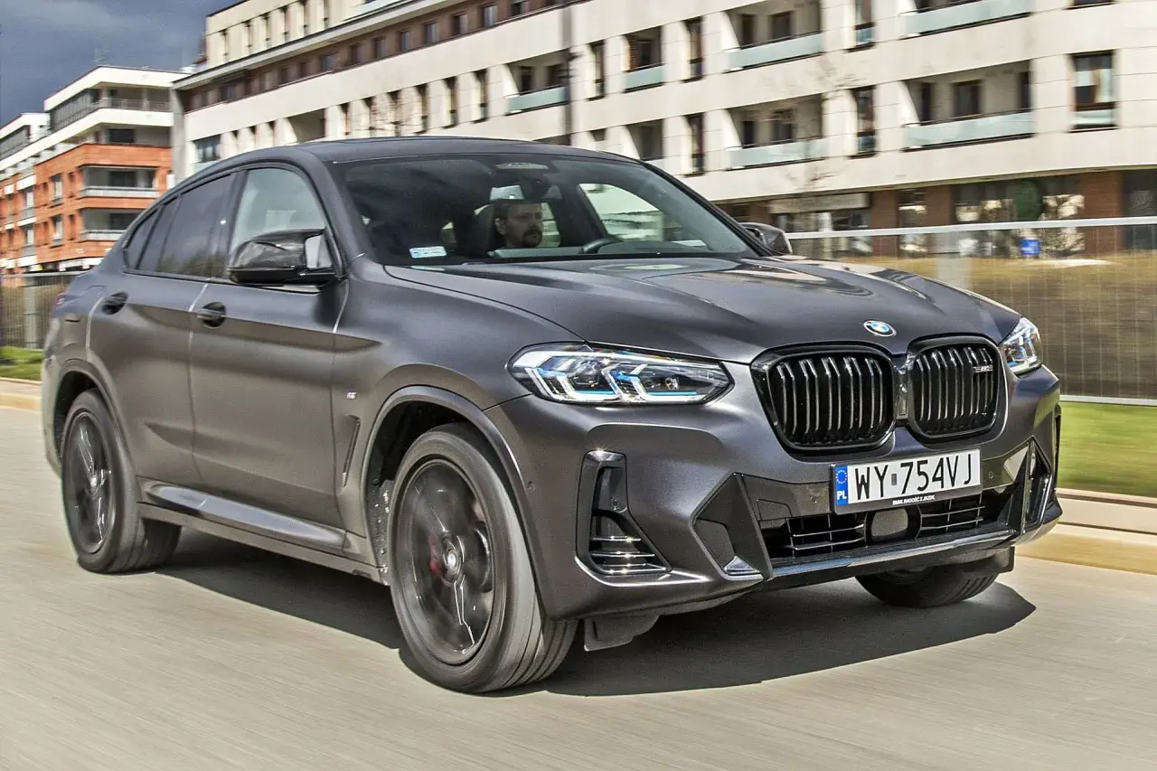Eleganckie BMW X4 w kolorze grafitowym pędzi ulicą, za kierownicą siedzi mężczyzna.