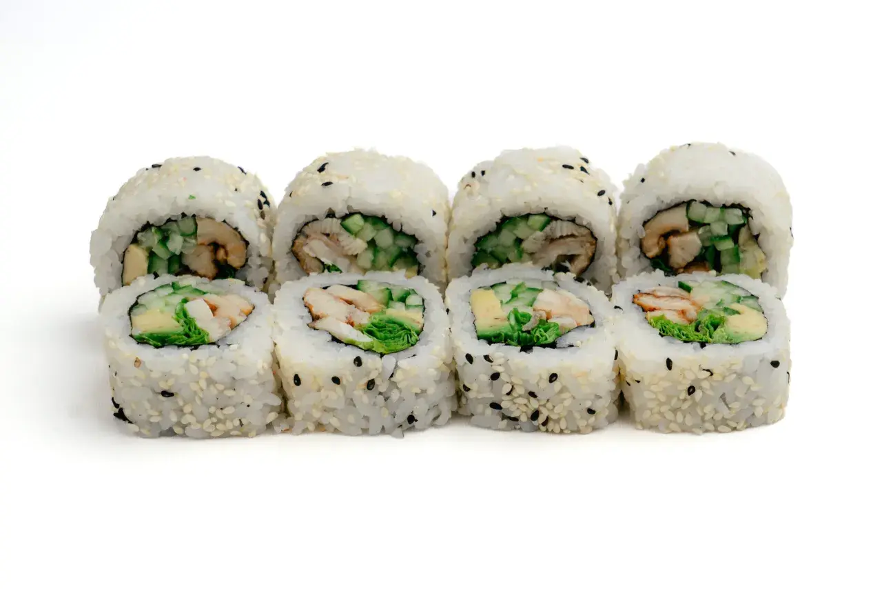 Rząd roladek sushi z ryżem, sezamem i kawałkami unagi, ogórka i awokado.