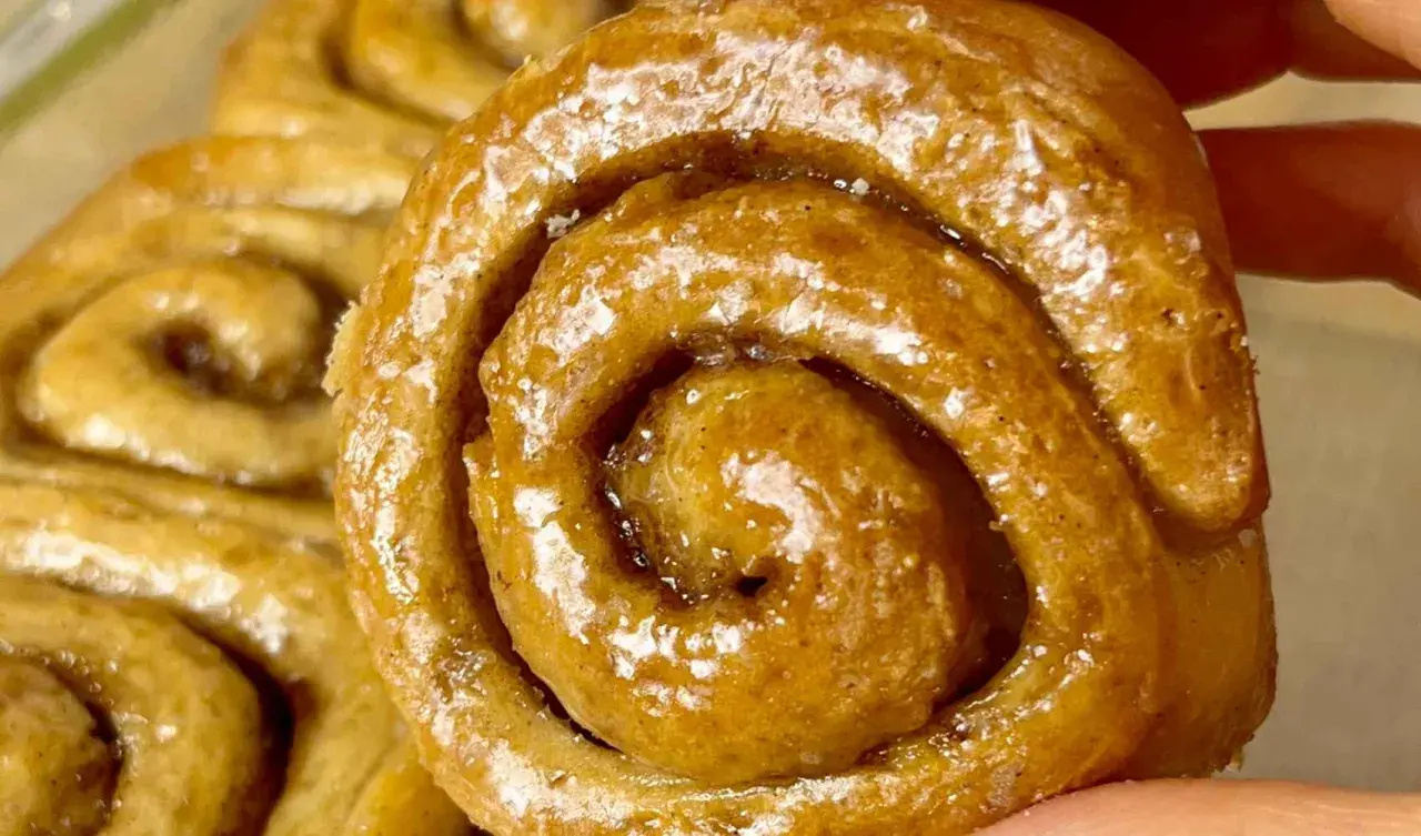 Un primo piano di soffici cinnamon rolls glassati, con la loro spirale invitante e il profumo di cannella che sembra quasi percepibile.