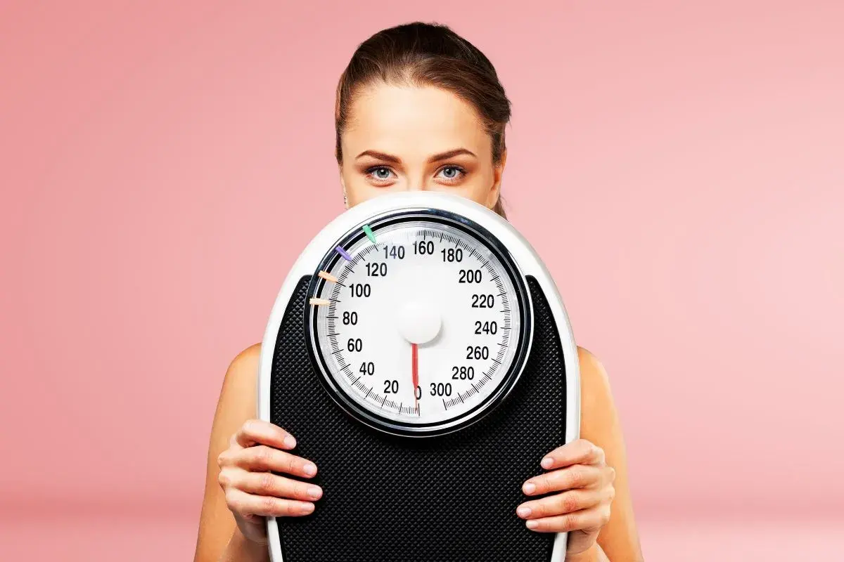 Donna con bilancia, un simbolo per la dieta 1500 calorie e il controllo del peso.