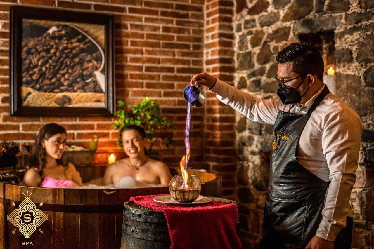 Pareja disfruta de un baño de chocolate spa mientras un mesero vierte líquido en llamas.