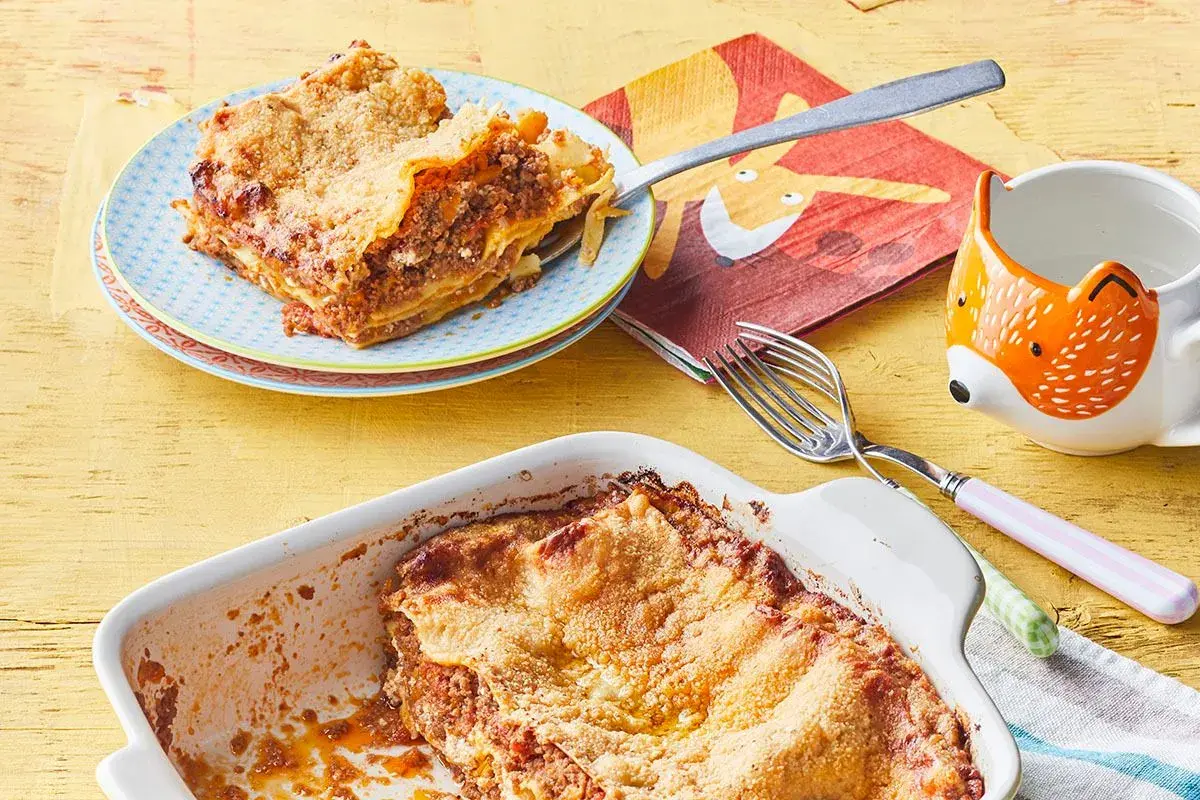 Lasagne maison : une part de recette lasagne ricotta viande hachée sur une assiette, le plat encore plein à côté.