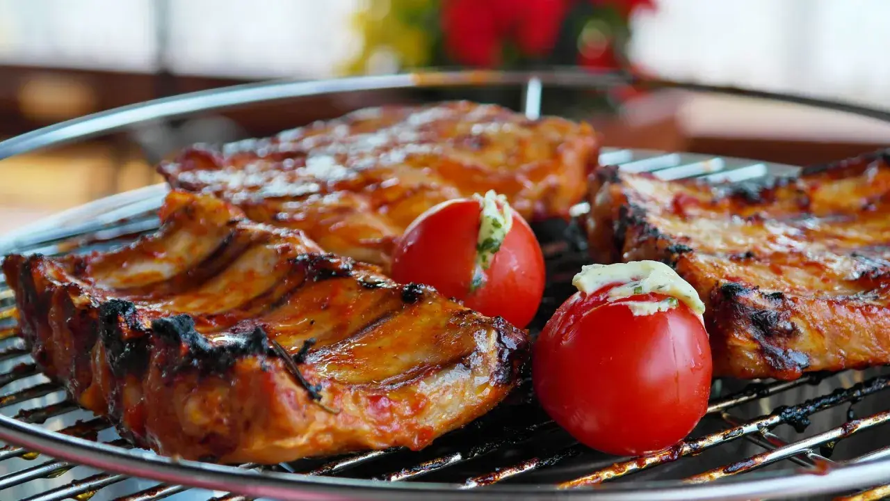 Côtelettes de porc grillées, savourant la qualité de la viande espagnole, accompagnées de tomates farcies.