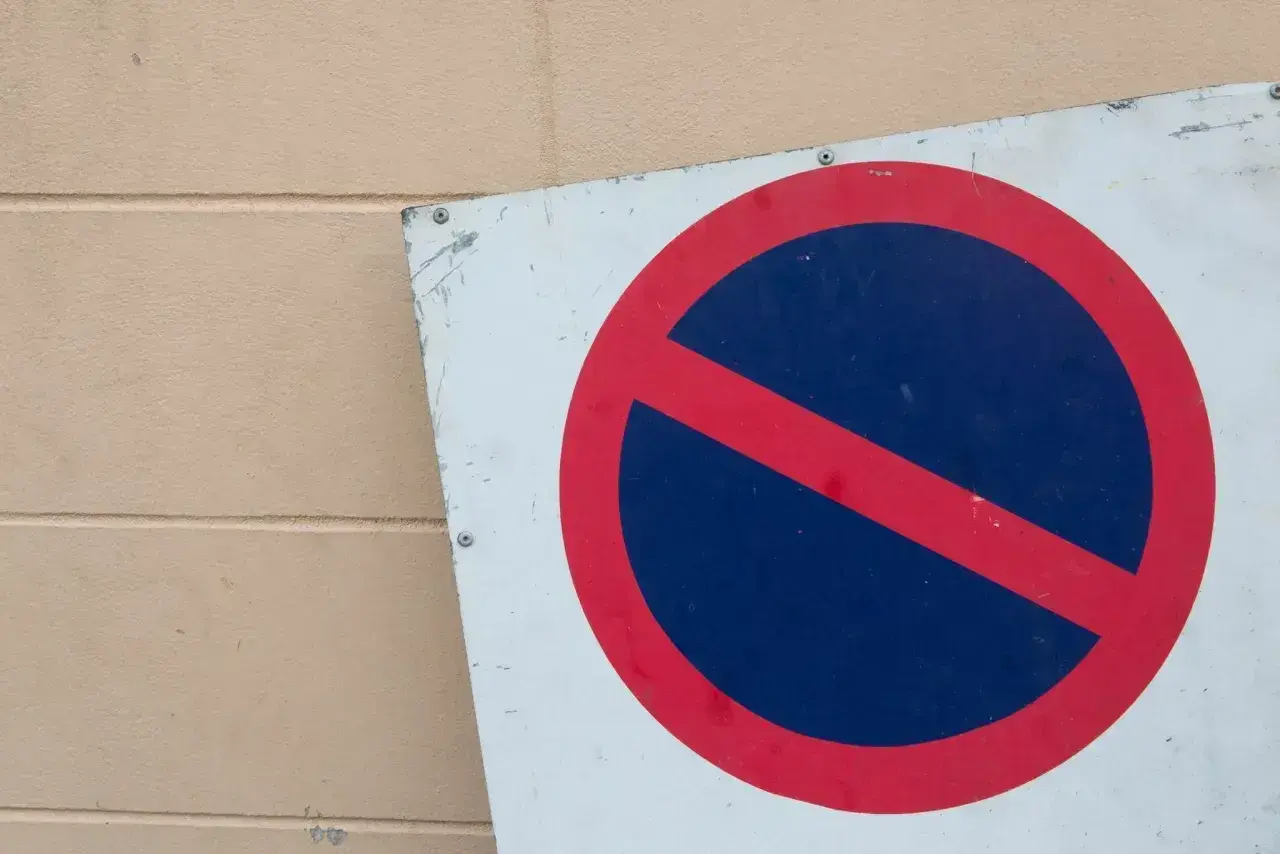 Znak b35 zakazu zatrzymywania się. Czerwone koło z czerwoną przekątną na niebieskim tle.