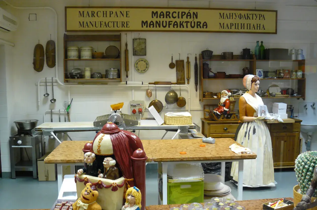 Wystawa w muzeum marcepanu Eger: kuchnia z manekinami, narzędziami i słodkimi dekoracjami.
