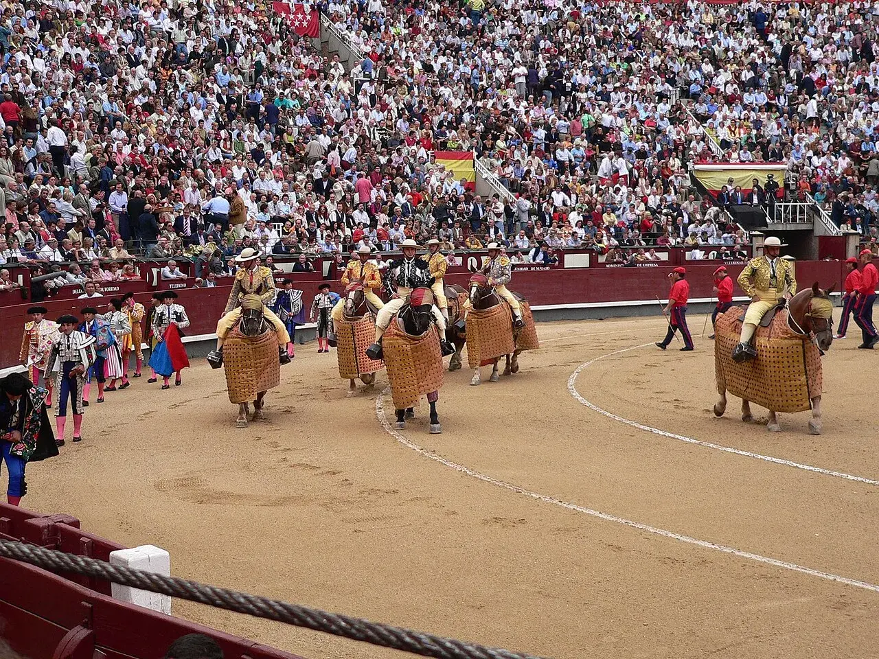 Inicio de que es una corrida de toros: picadores a caballo con caparazones, toreros y público en las gradas.