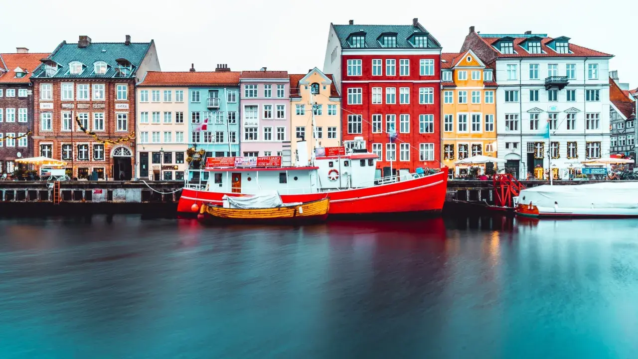 Bateaux rouges et jaunes amarrés devant des maisons colorées, typiques de Copenhague.