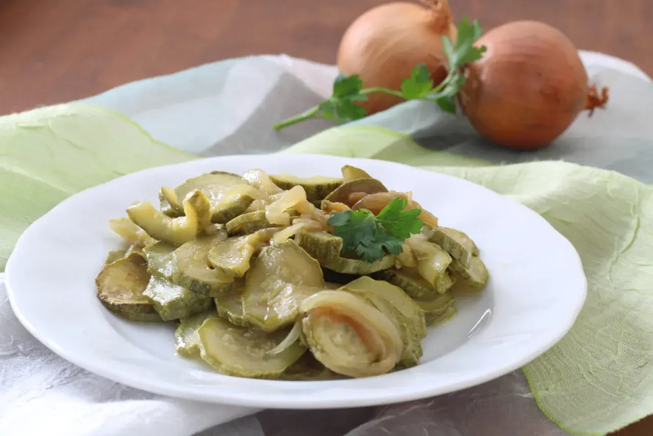 Zucchine in padella con cipolla, un contorno semplice e gustoso, guarnito con prezzemolo fresco.