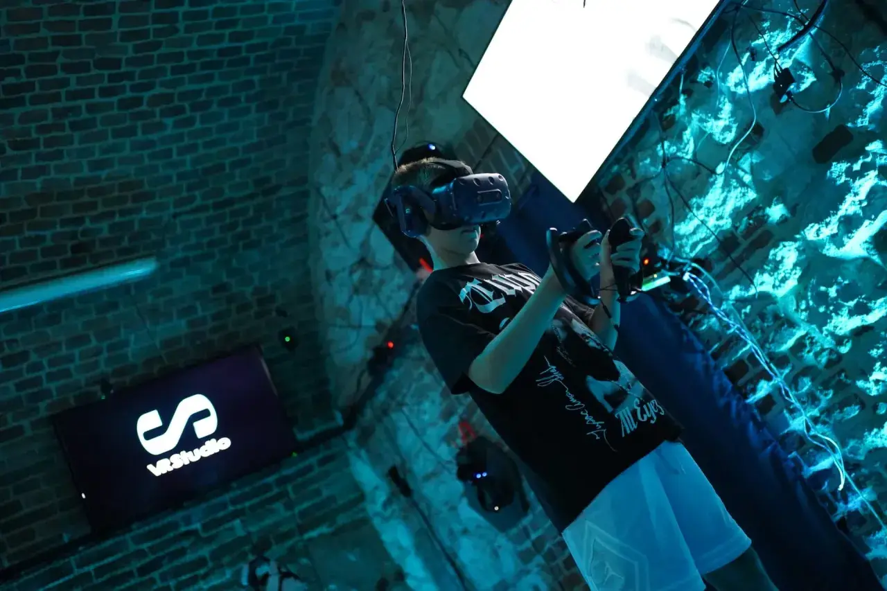 Chłopak w goglach VR w Krakowie, zanurzony w wirtualnej rzeczywistości. Na ekranie logo VRStudio.