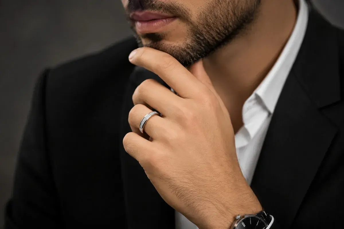 Un hombre con traje negro y camisa blanca luce un elegante anillo bulgari oro blanco y amarillo, adornado con diamantes.