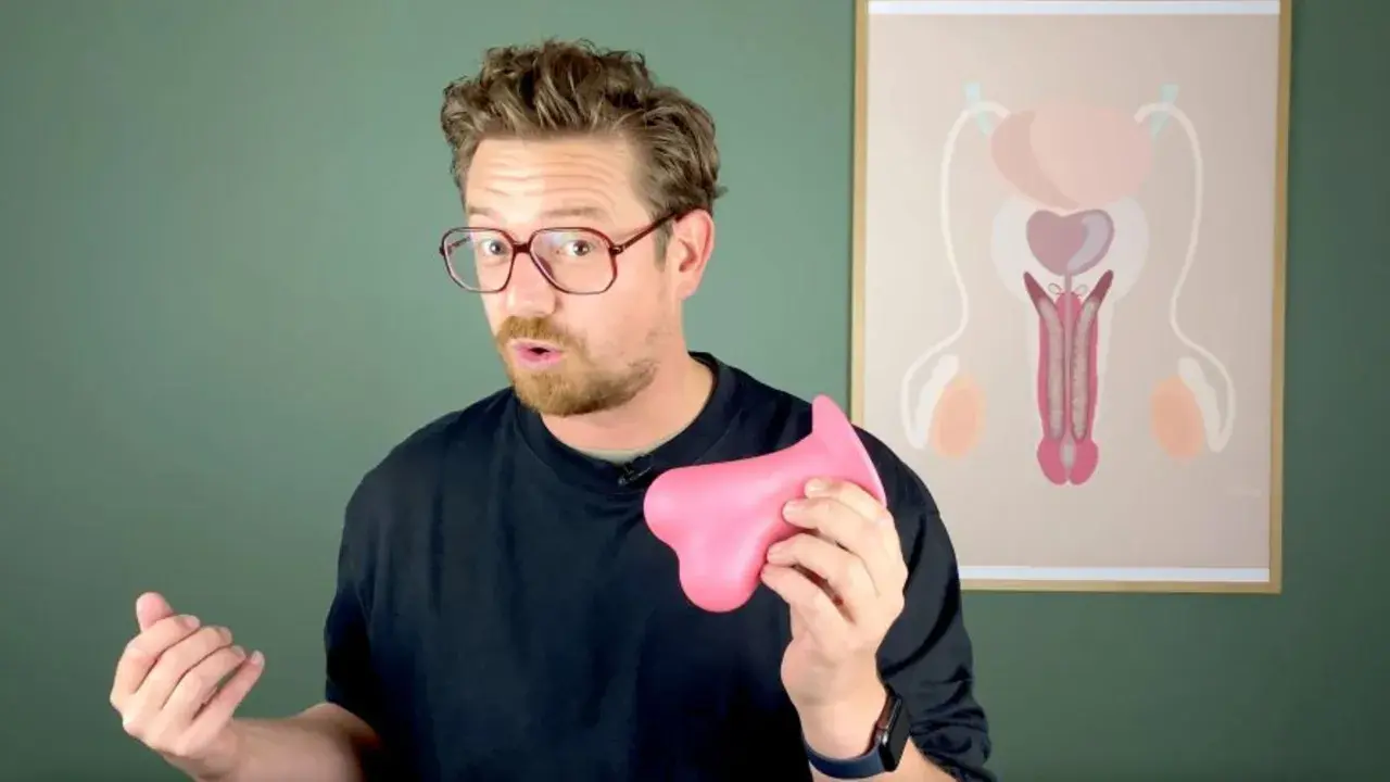 Mann mit Brille hält rosa Objekt. Im Hintergrund eine Grafik des männlichen Genitalbereichs, die Fragen zu Creatin Nebenwirkungen Hoden aufwirft.