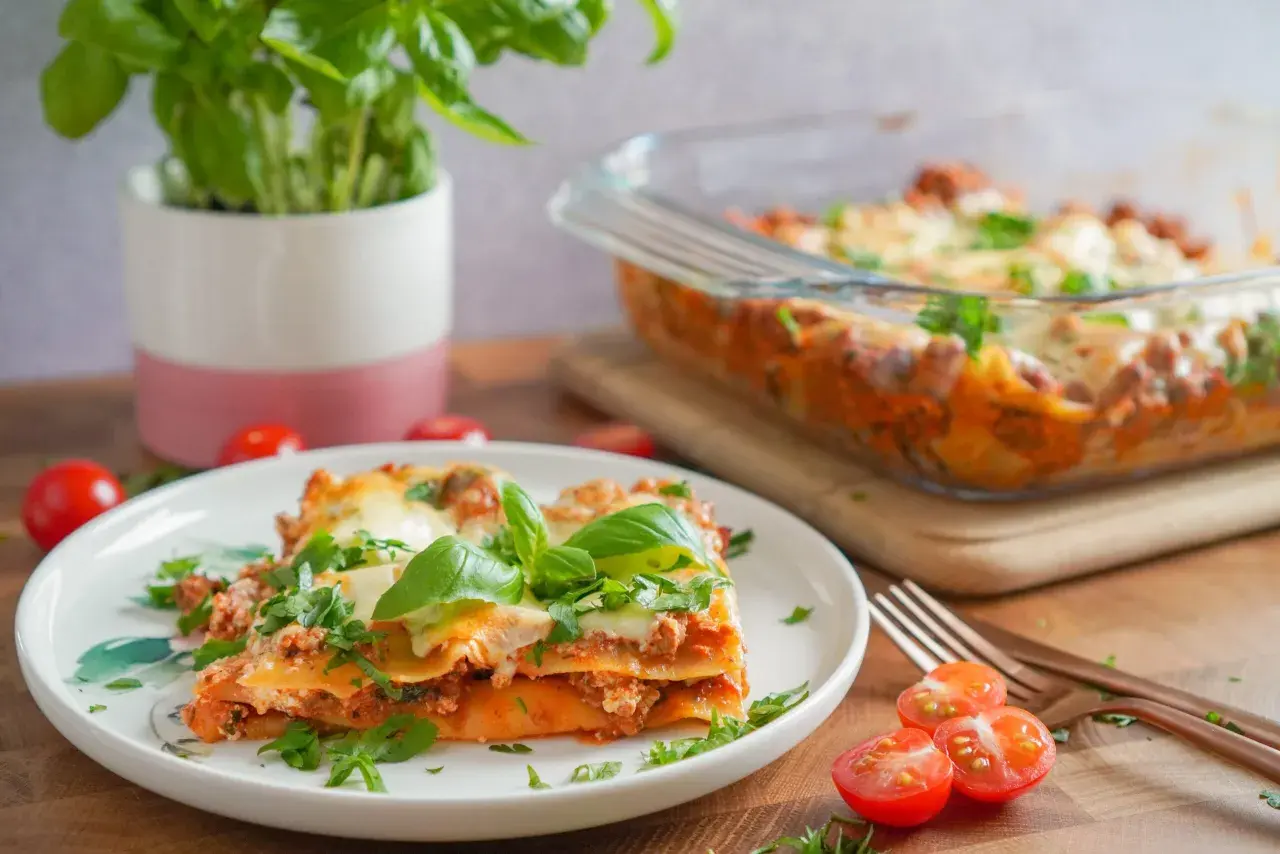 Pyszna lasagne na talerzu, z bazylią i pomidorkami. Idealnie, gdy zastanawiasz się, co podać do lasagne.