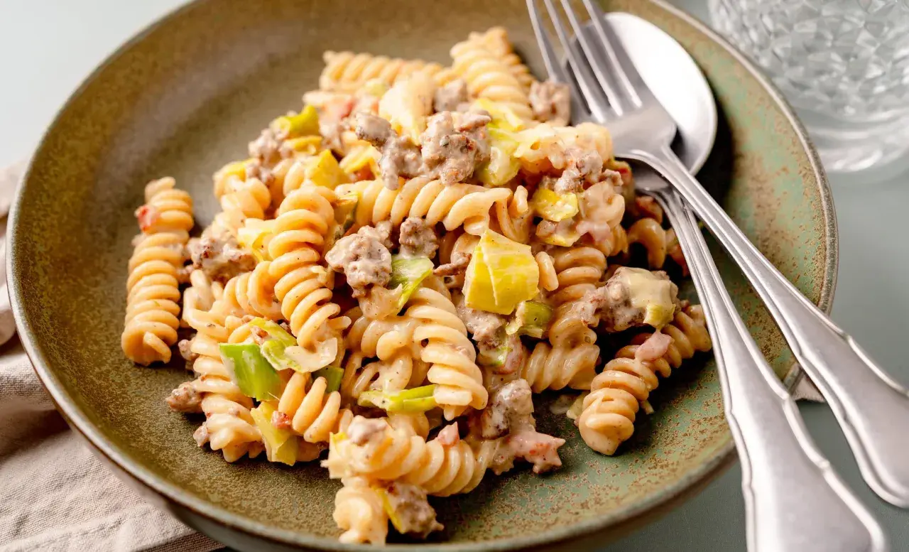 Herzhafte Hackfleisch Lauch Pfanne mit Spiralnudeln, cremig und appetitlich auf einem rustikalen Teller angerichtet.