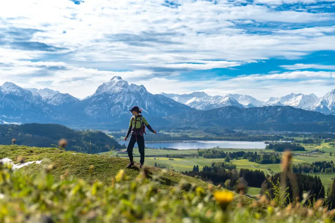 Wanderin genießt Ausblick auf Alpenpanorama, ein perfekter Moment auf den Fernwanderwegen Alpen.