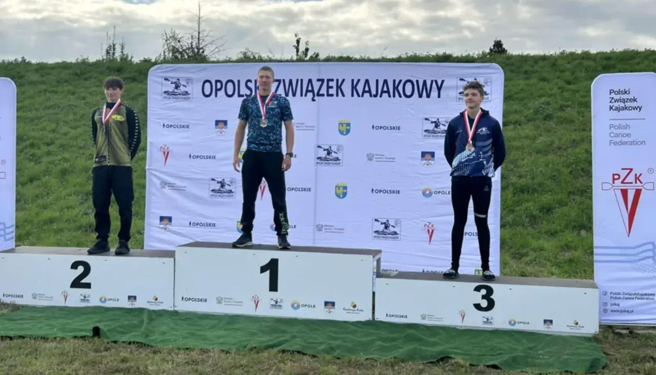 Trzech młodych mężczyzn na podium z medalami, na tle baneru Opolszczyzny.