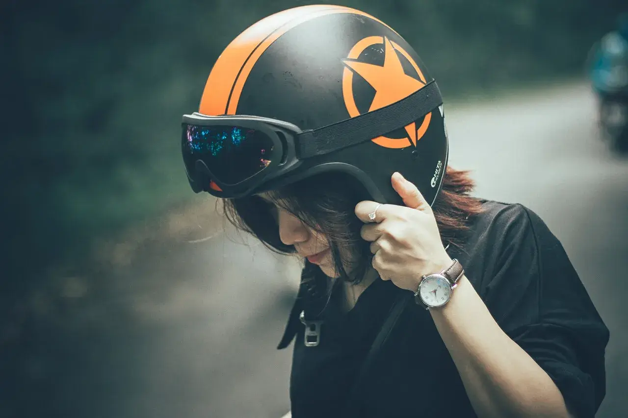 Ragazza con casco moto nero e arancione, occhiali riflettenti. Guida sicura: ecco come scegliere casco moto.