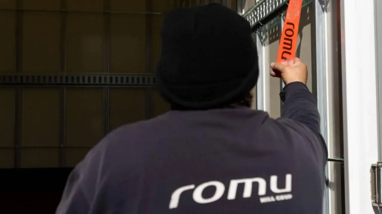 Persona con gorro negro asegura trincajes de cargas con una cinta naranja de la marca Romu.