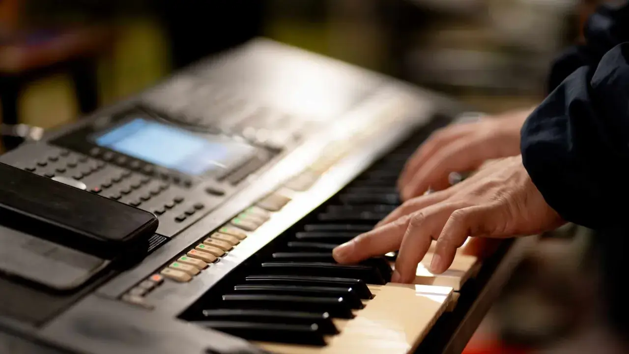 Dłonie grające na keyboardzie, tworząc muzykę. To jest keyboard.