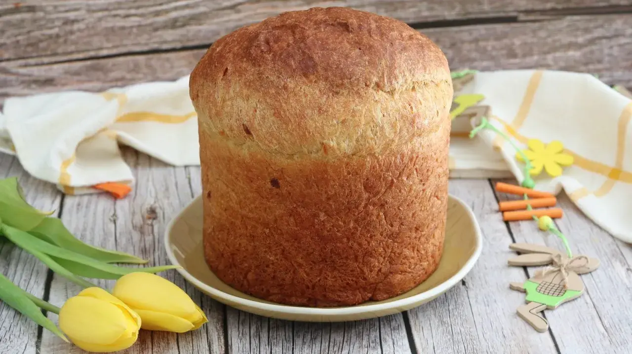 Gâteau de Pâques italien doré, prêt à être décoré d'œufs durs. Tulipes jaunes et décorations de lapin apportent une touche festive.