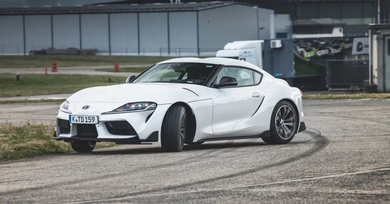 Biała Toyota GR Supra na torze, zostawiająca ślady opon.