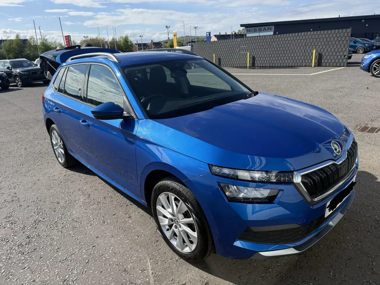Blå Skoda Kamiq parkerad utomhus, med bagageluckan öppen. En potentiell skoda kamiq problem kan vara att den är för stor för att få plats i garaget.
