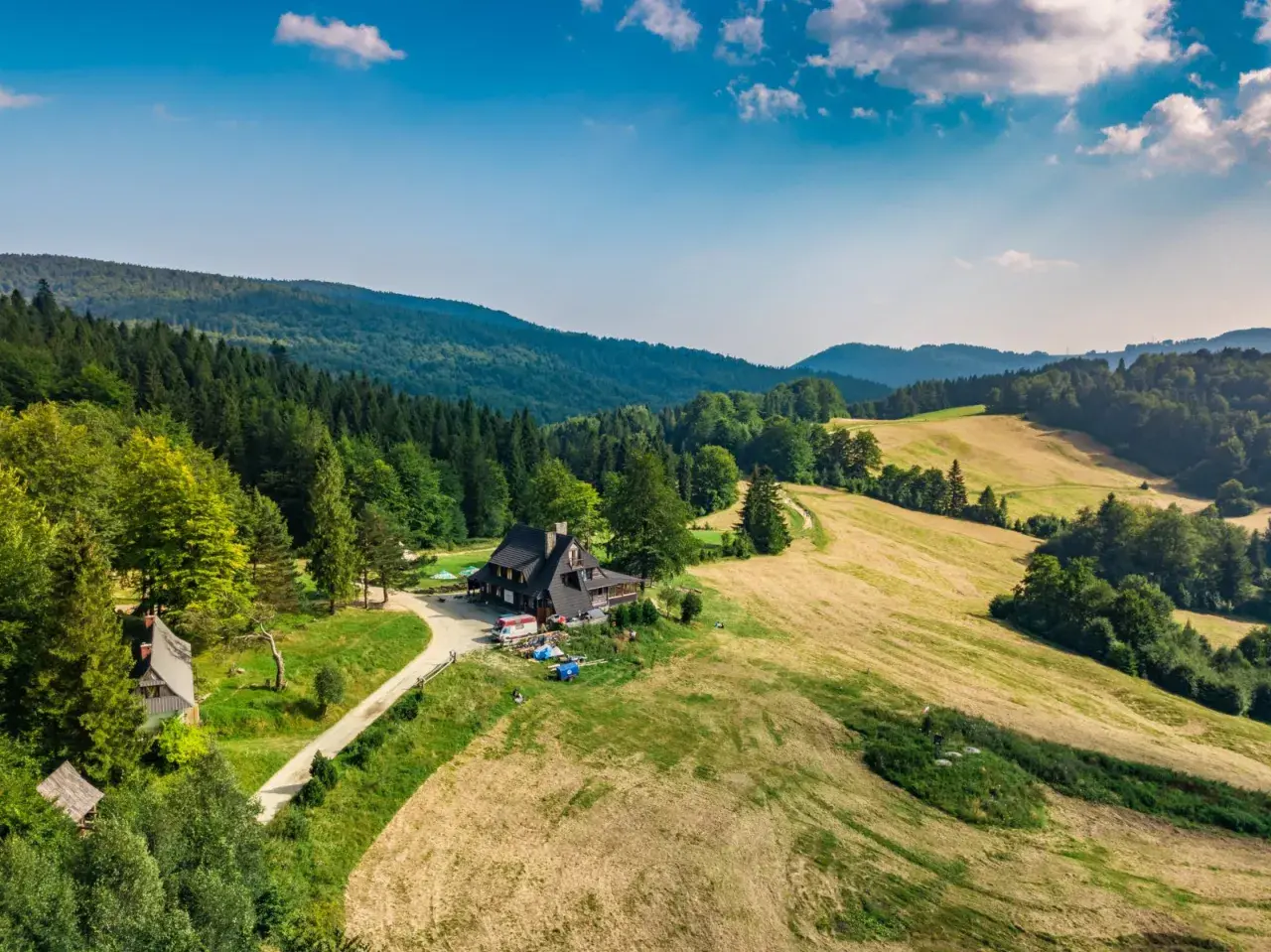 Malownicza bacówka nad Wierchomlą, gdzie trasa turystyczna prowadzi przez zielone wzgórza i lasy.