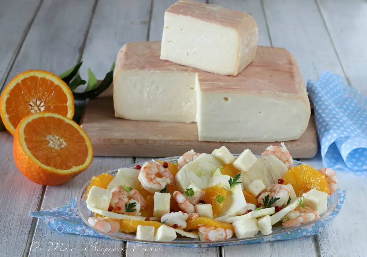 Un blocco di formaggio taleggio stagionato, pronto per essere gustato con un'insalata fresca di arance, finocchi e gamberetti.