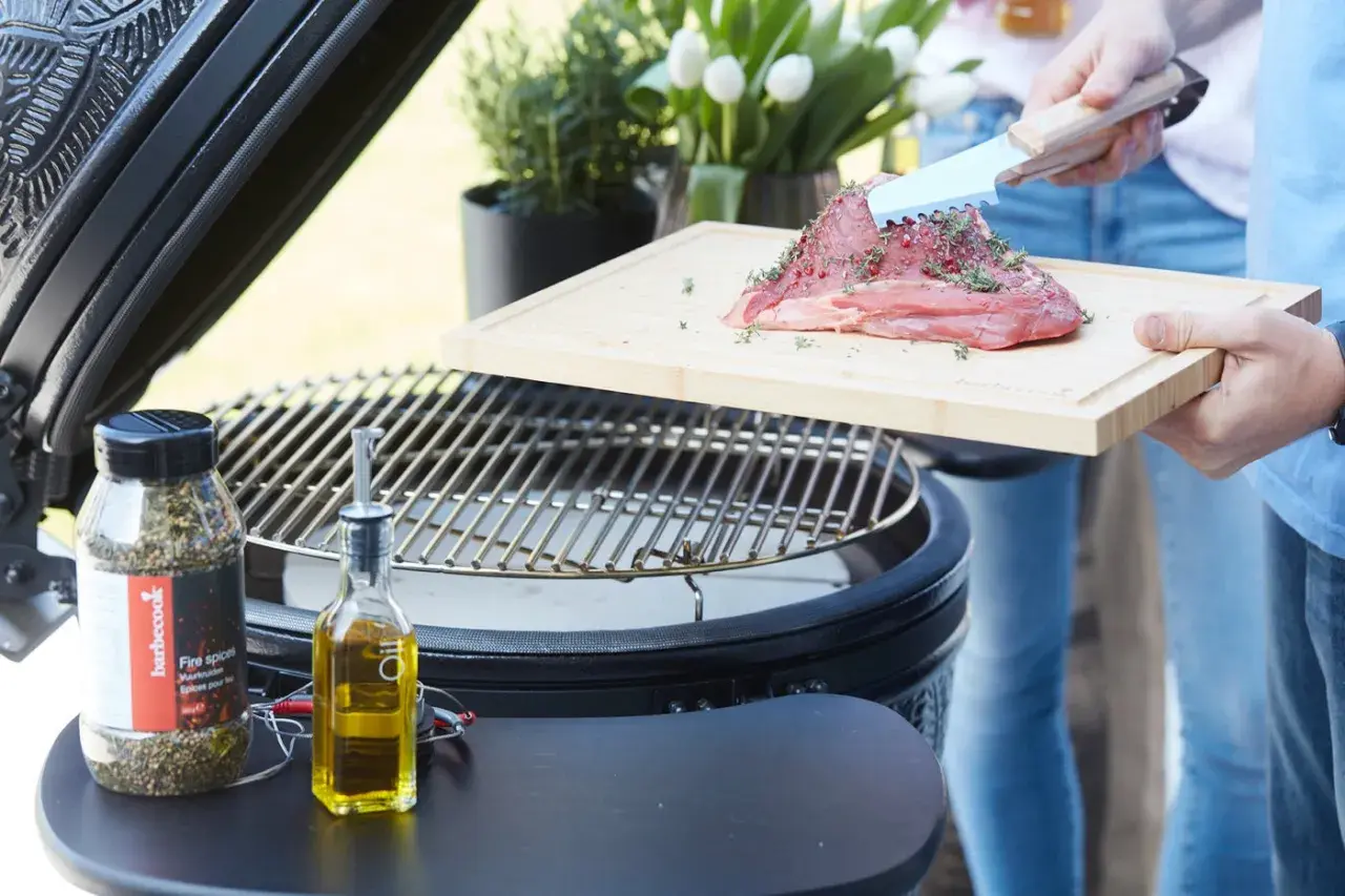 Préparation d'un morceau de bœuf Black Angus assaisonné, prêt à être grillé sur un barbecue. Huile d'olive et épices à proximité.