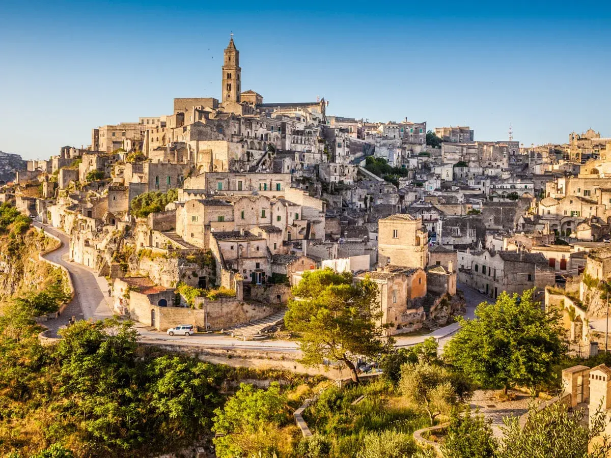 A panoramic view of Matera, Italy, showcasing its ancient cave dwellings and stone buildings cascading down a hillside, resembling a natural map.