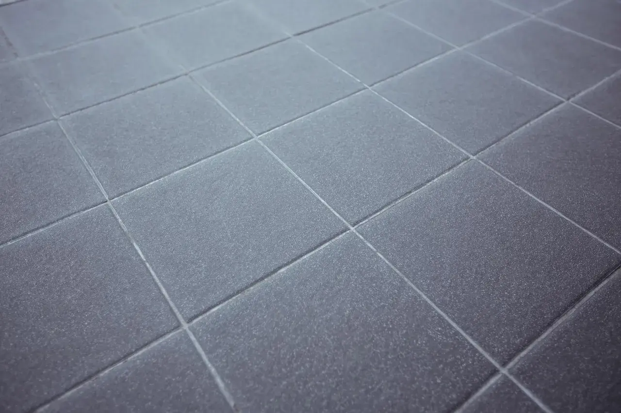 Dettaglio di piastrelle grigie con fughe pavimento pulite e uniformi, che creano un motivo geometrico ordinato.