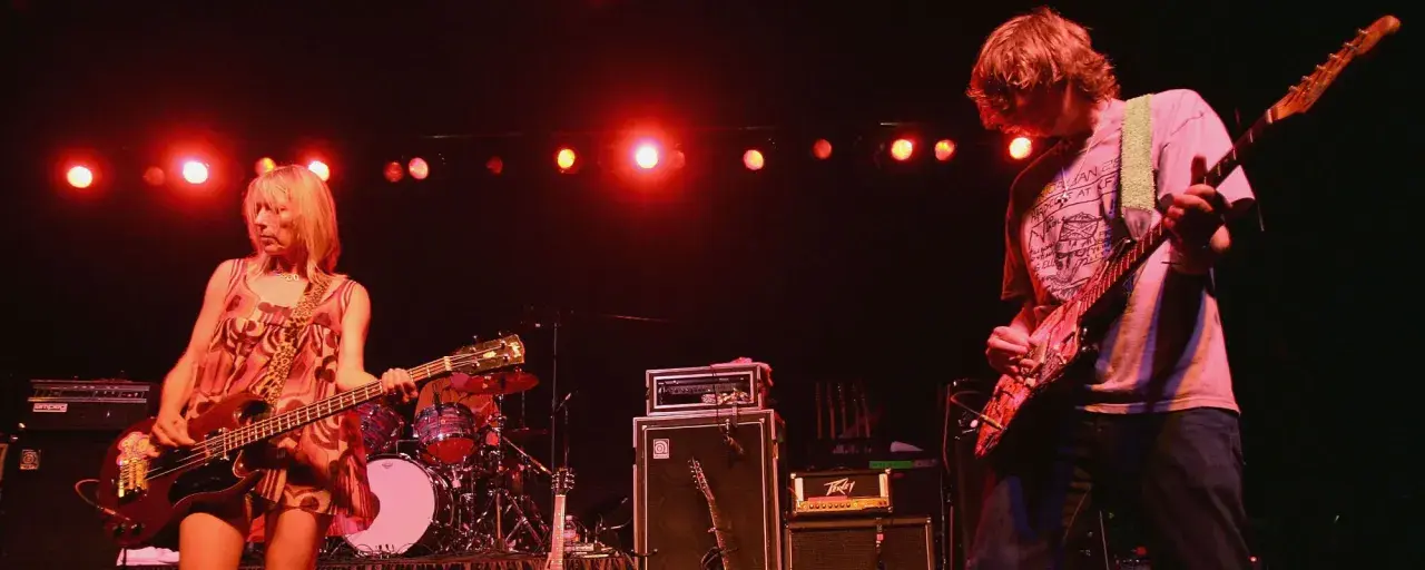 Kim Gordon i Thurston Moore z Sonic Youth grają na scenie, tworząc muzykę w stylu "Kool Thing".
