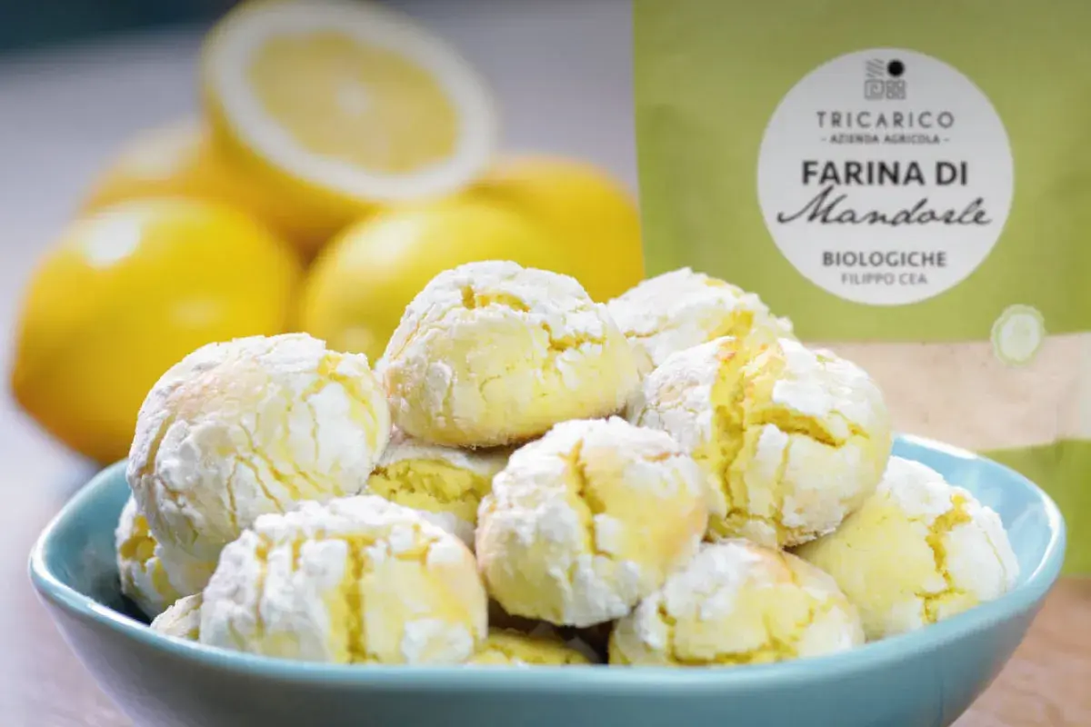 Biscotti con farina di mandorle, morbidi e profumati, accanto a limoni freschi e una confezione di farina.