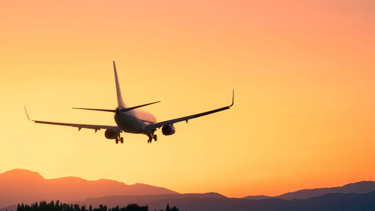 Flugzeug im Landeanflug bei Sonnenuntergang. Man fragt sich, wie viel eher am Flughafen sein, um diesen Anblick zu genießen.