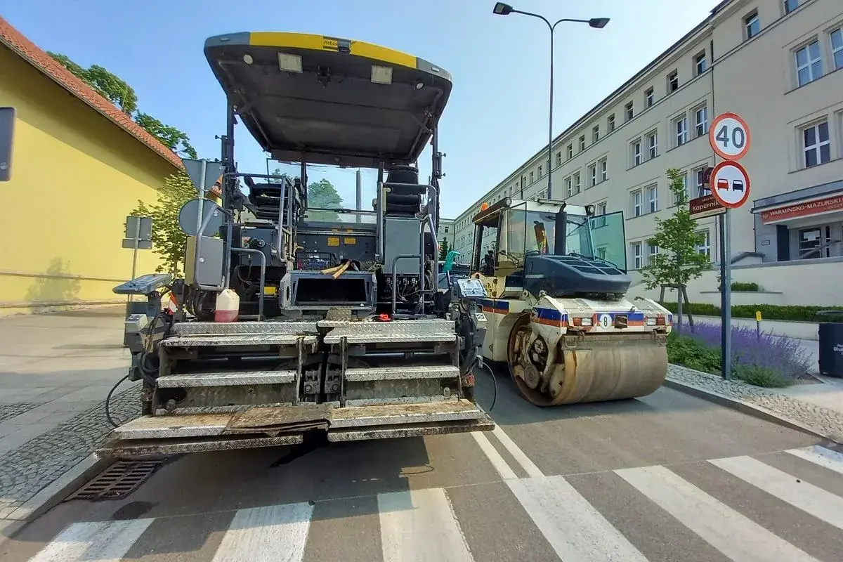 Asfaltarka i walec drogowy na pasach dla pieszych w Olsztynie.