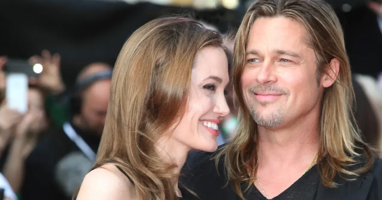 Angelina Jolie i jej mąż Brad Pitt uśmiechają się do siebie na czerwonym dywanie.