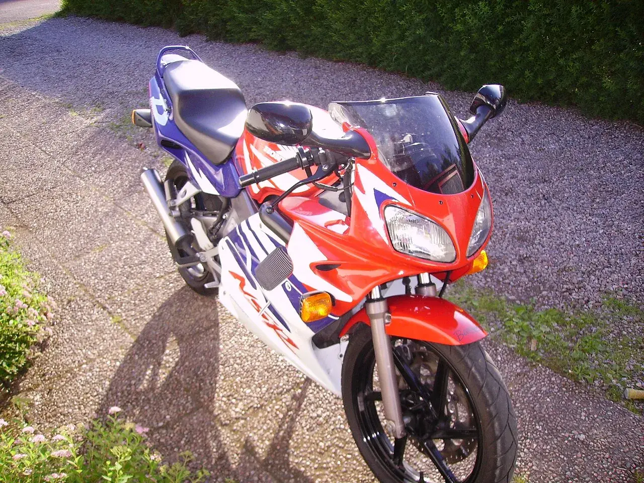 Sportowy motocykl Honda NSR 125 w czerwono-biało-niebieskich barwach, idealny do poznawania jego danych technicznych.