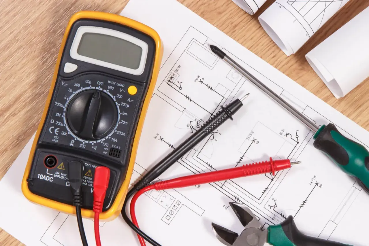 Narzędzia elektryka i schemat instalacji elektrycznej. Multimetr, śrubokręt, kombinerki i przewody gotowe do wykonania oświadczenia elektryka o wykonaniu instalacji elektrycznej.