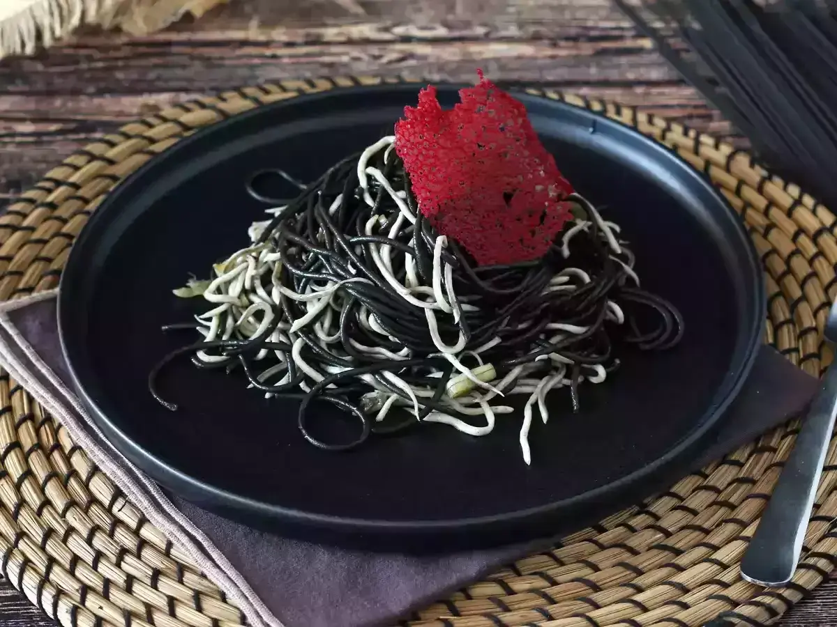 Spaghetti neri e bianchi, un contrasto elegante. Il nero di seppia dona un sapore unico a questo piatto, guarnito con una cialda rossa croccante.