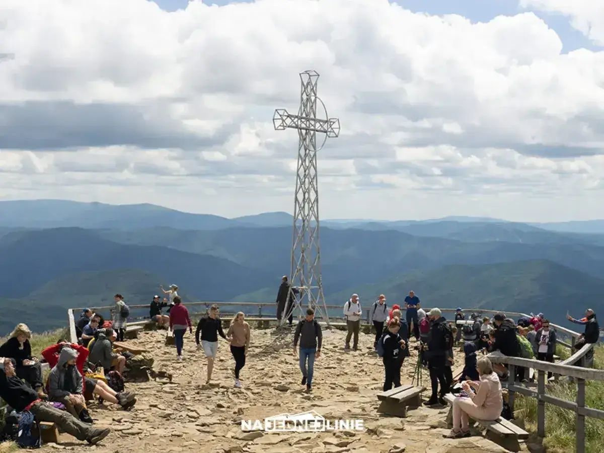 Tłum turystów na szczycie Tarnicy w Bieszczadach, podziwiających rozległą panoramę gór.