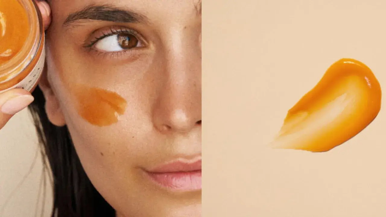 Un masque visage orangé appliqué sur la joue d'une femme. La question est : combien de temps garder un masque visage pour un soin optimal ?