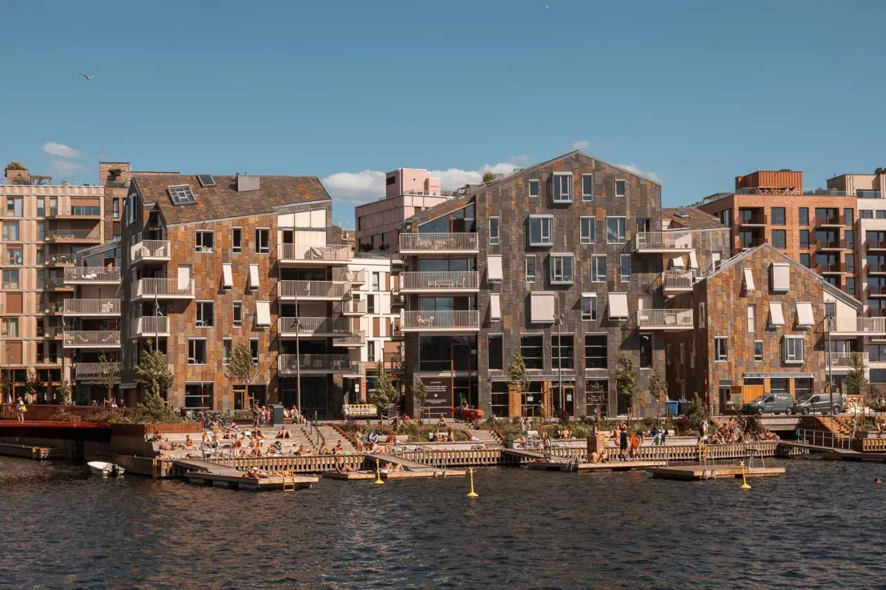 Moderne Architektur am Wasser in Oslo. Menschen entspannen sich auf Holzdecks, ein perfekter Ort für Oslo Sightseeing.