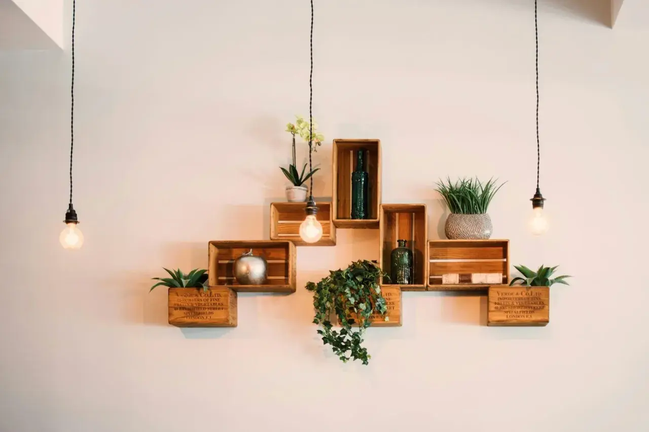 Scaffali in legno a forma di cassa, decorati con piante e oggetti, mostrano come attaccare una mensola al muro con stile.