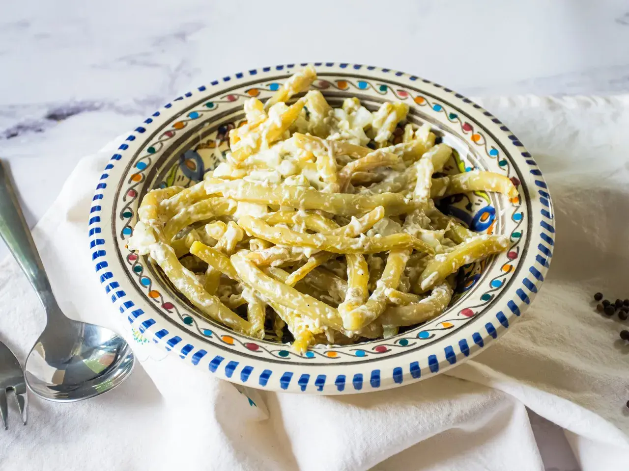Ein cremiger Bohnensalat mit Sahne, serviert in einer bunten Schüssel. Ein leckeres Gericht, das zum Genießen einlädt.