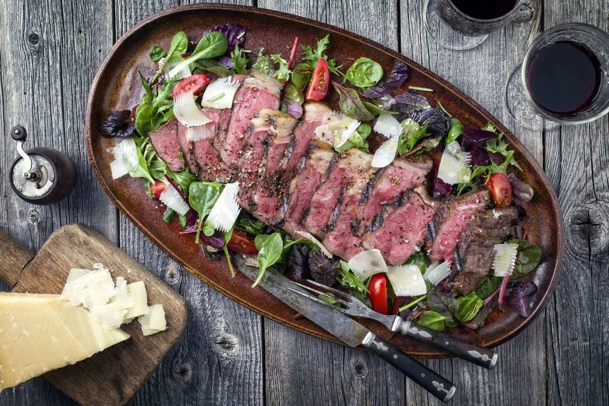 Tagliata succulenta in friggitrice ad aria, servita con insalata mista, scaglie di parmigiano e pomodorini.