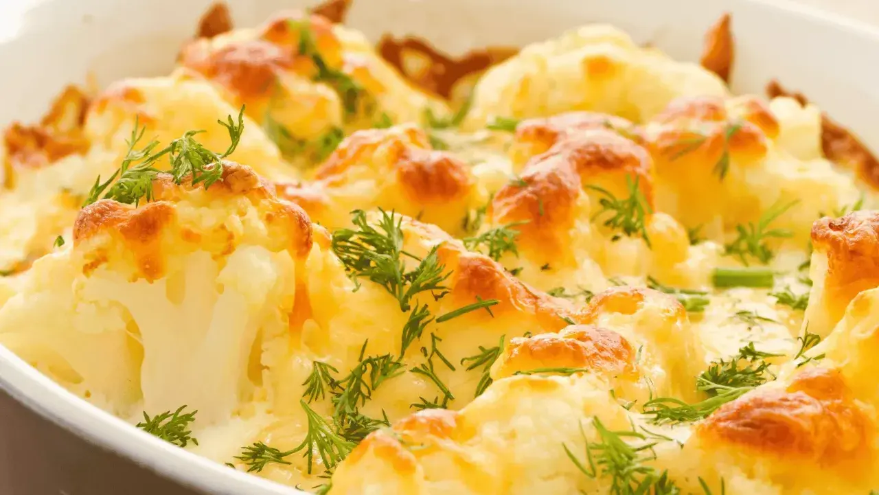 Coliflor asada gratinada con queso y hierbas frescas. Un plato reconfortante y delicioso.