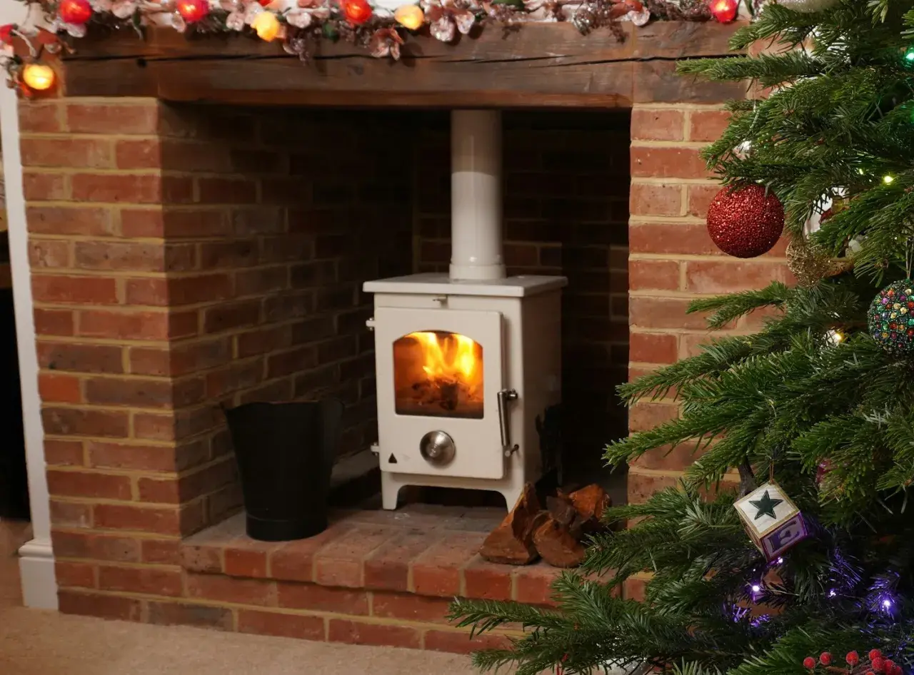 Installation d'un poêle à granulés avec conduit existant dans une cheminée en briques, décorée pour Noël.