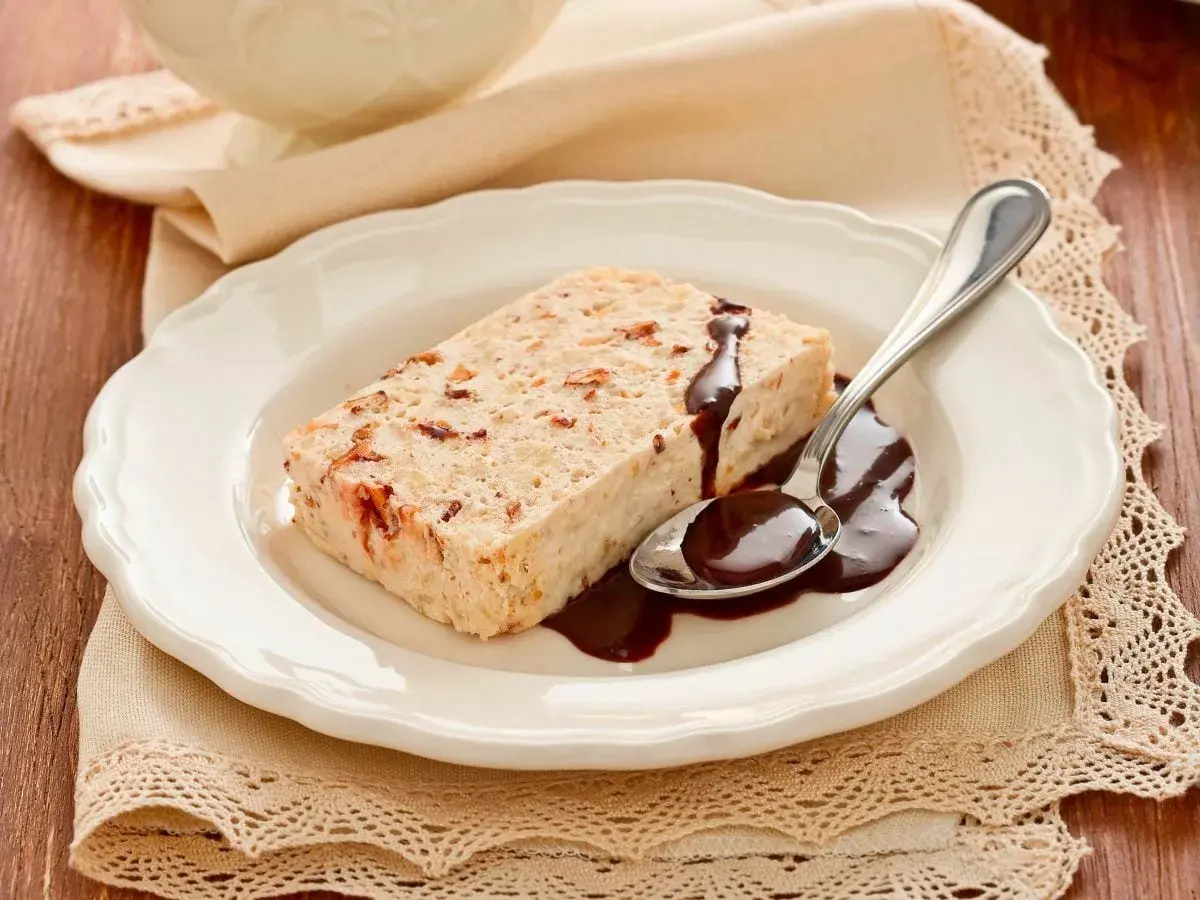 Delizioso semifreddo alla mandorla con salsa al cioccolato su un piatto bianco, pronto per essere gustato.