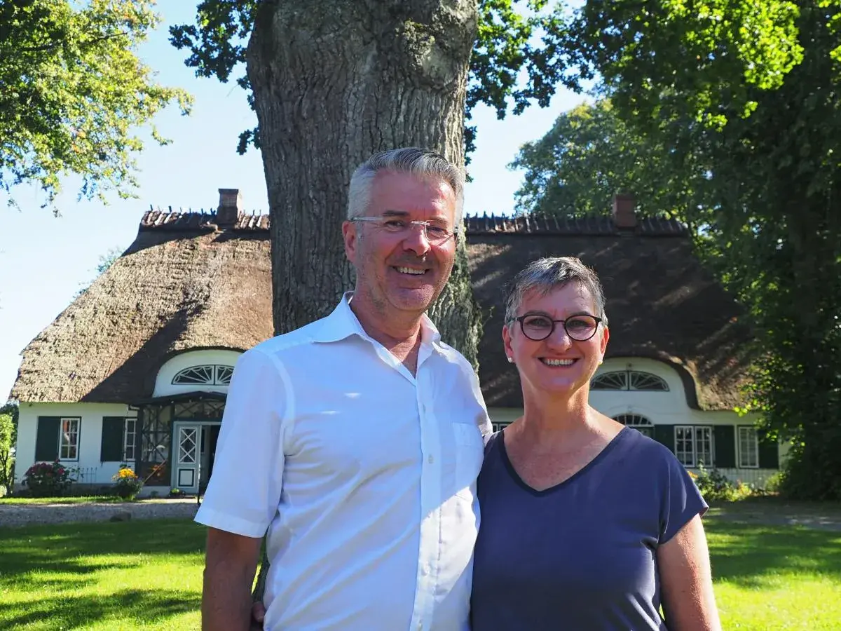 Ein Paar vor einem Reetdachhaus in Schleswig-Holstein, das am Tag des offenen Denkmals besichtigt werden kann.