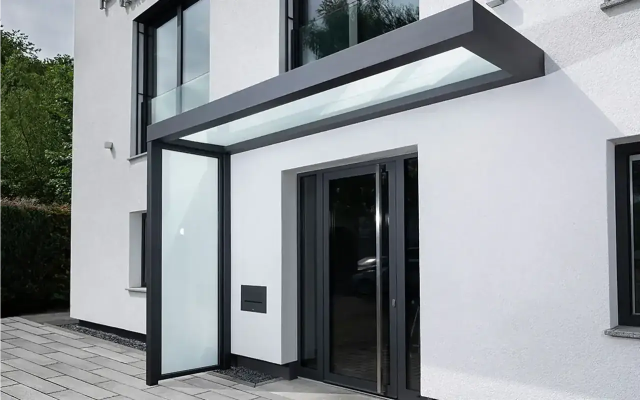 Moderne Ideen für ein Vordach am Hauseingang: Glas und Anthrazit schaffen einen eleganten Schutz.